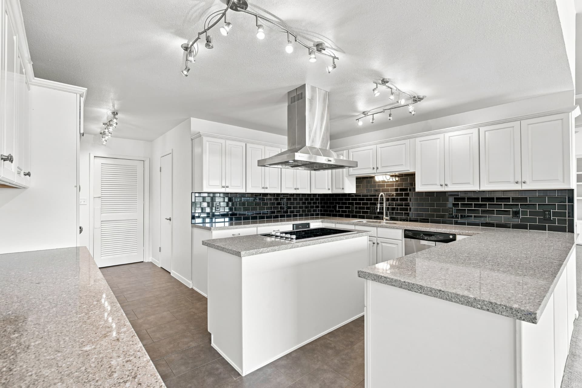 Kitchen with white cabinetry, granite counters, and black tile backsplash