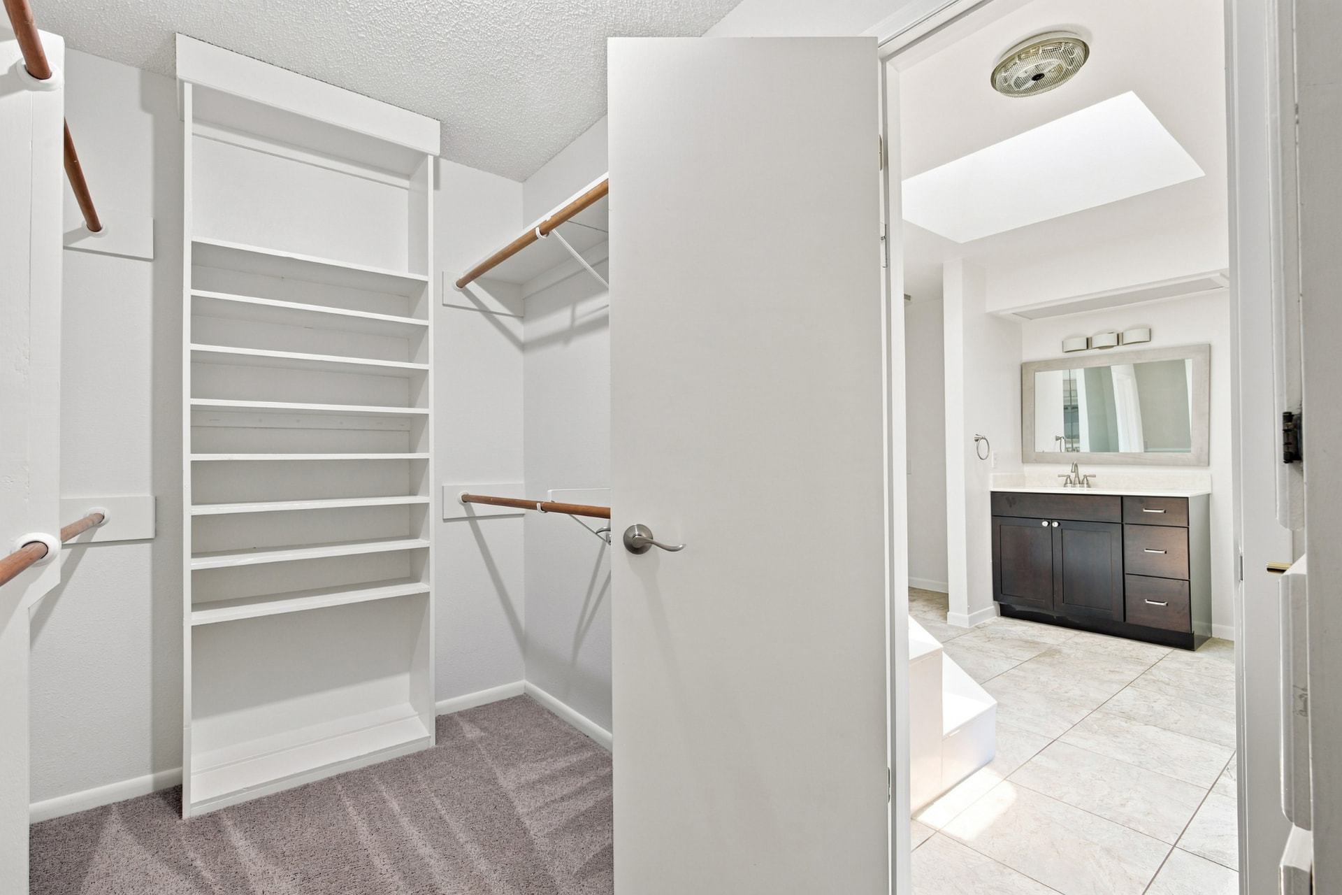Walk-in closet with shelving open to the primary bath
