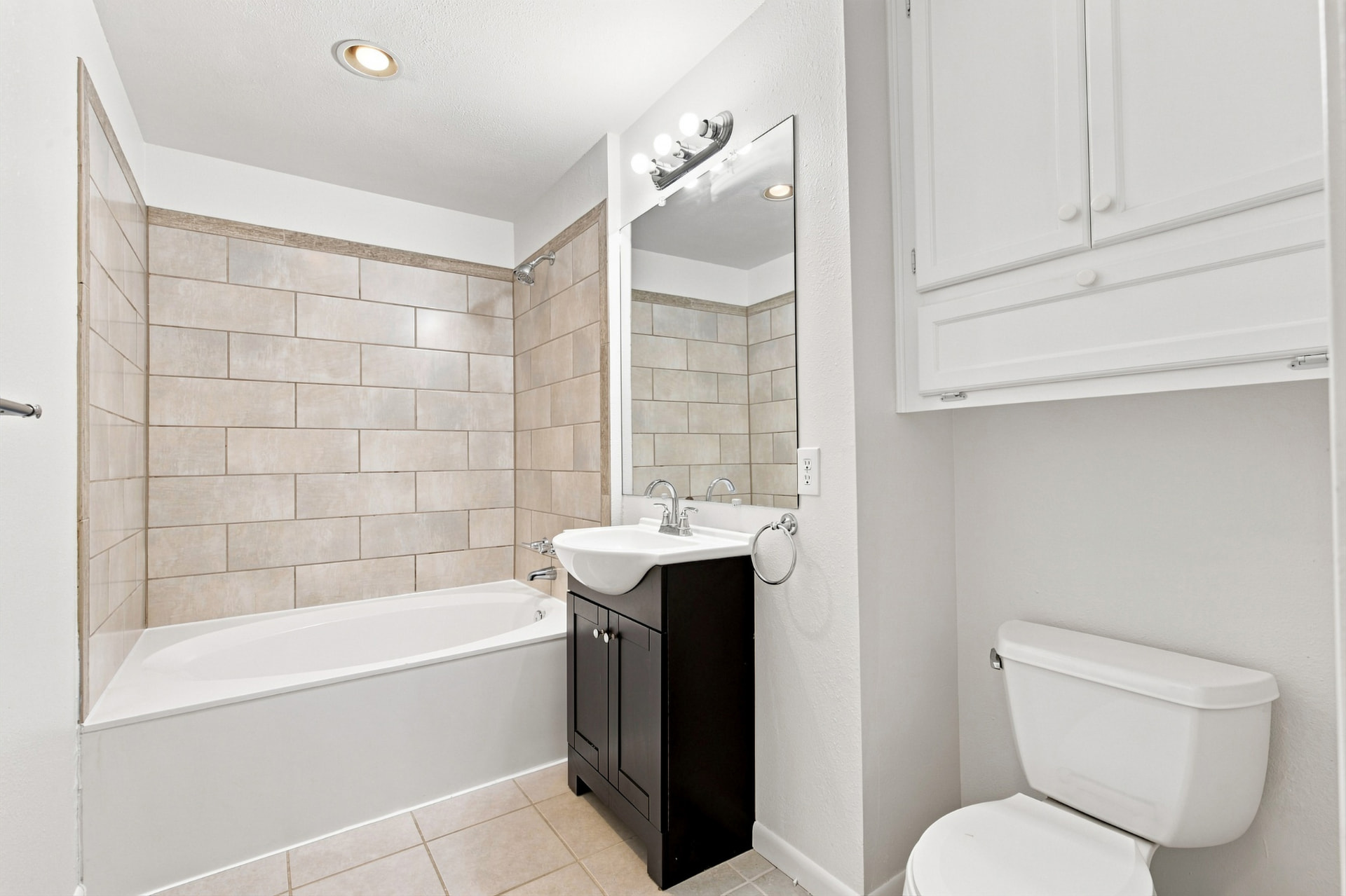 Guest bath with tiled tub surround and dark vanity