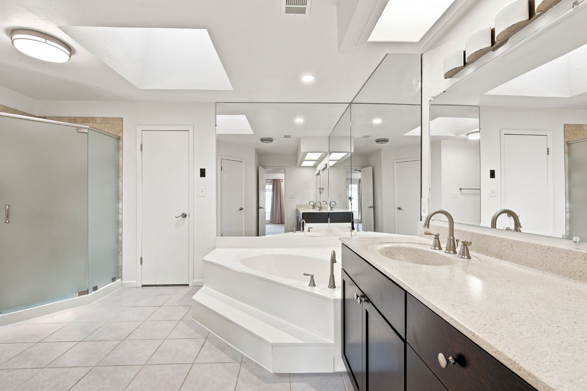 Primary bath with corner tub, glass shower, and long vanity