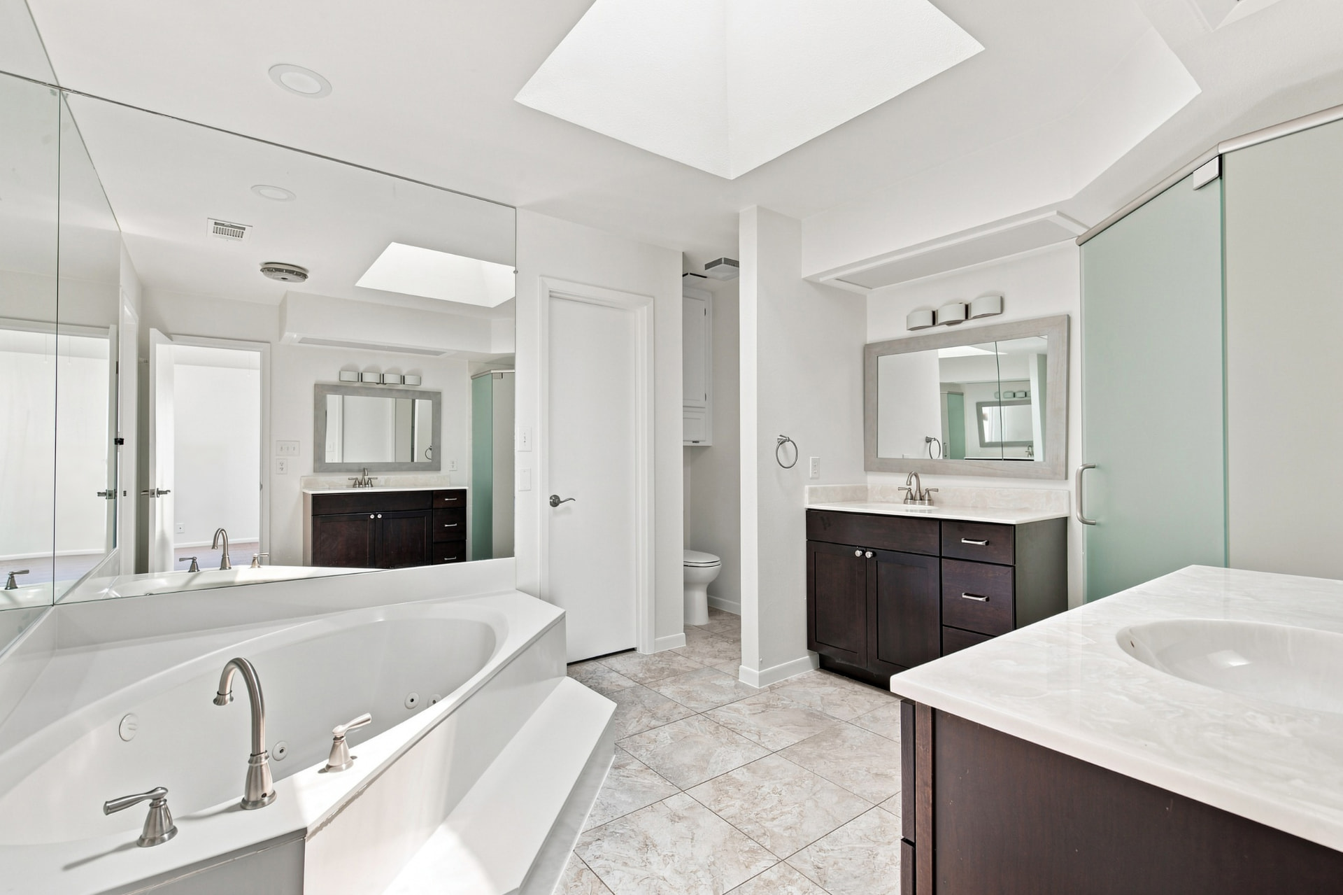 Primary bath with soaking tub, skylight, and dual vanities
