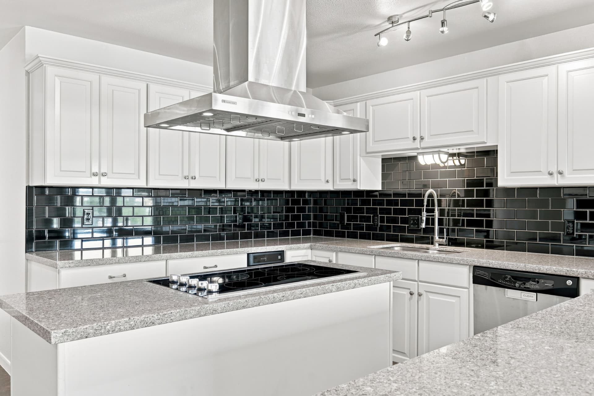 Island cooktop with stainless hood and gloss tile backsplash