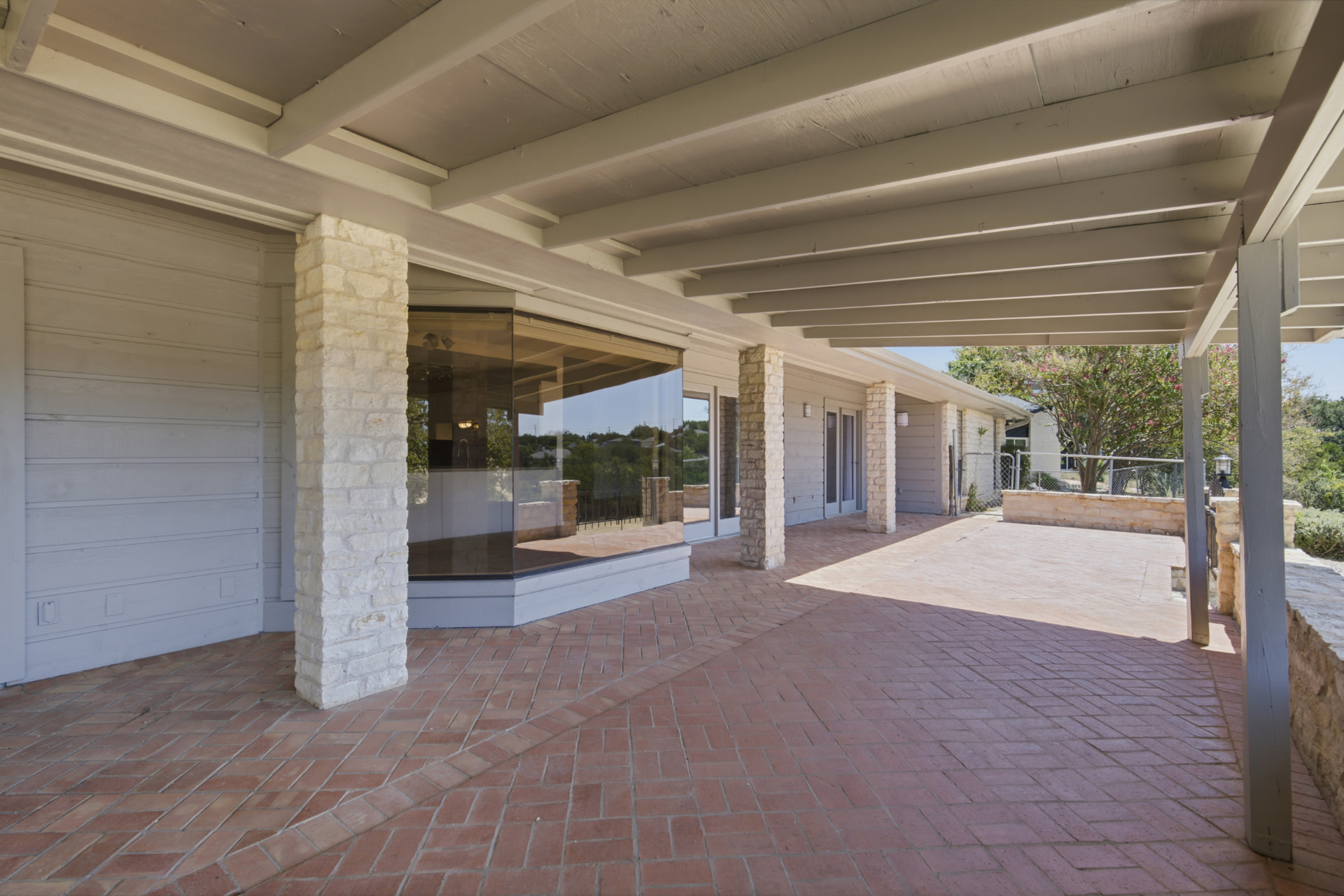 Stone columns and beamed patio ceiling along the rear of the home