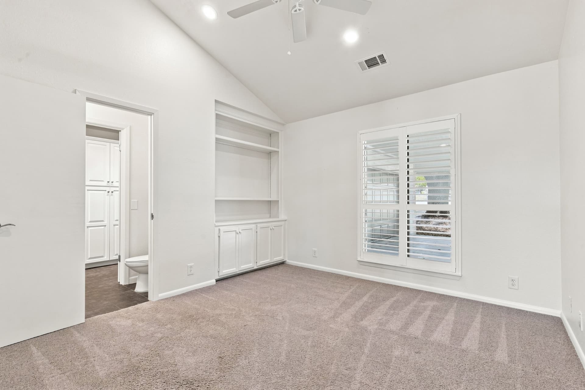 Bedroom with built-in shelving and en-suite bath beyond