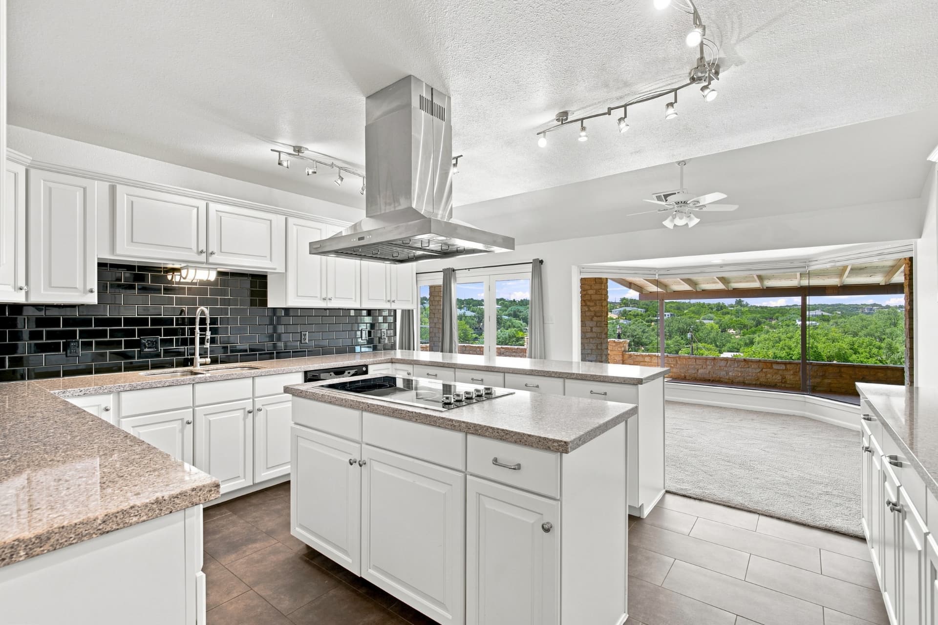Open kitchen with island cooktop looking out to the covered patio