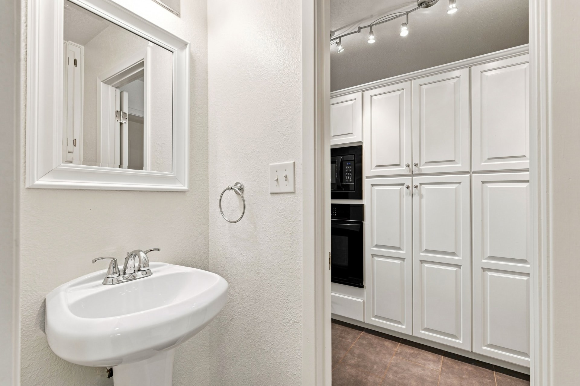 Powder room with pedestal sink beside the kitchen pantry wall